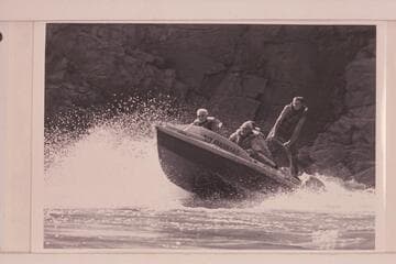 The "Rattlesnake" in Mile 217 Rapid, Grand Canyon.  Joe Desloge is at the left, Rod Sanderson is the pilot and Hugh Cutler is in back of him.  Argwen Bundy stands on the after deck bracing against a rope bridle