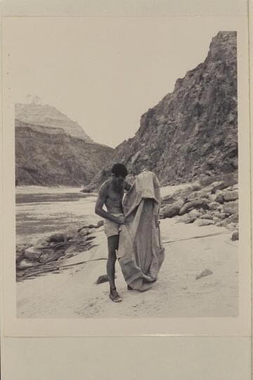 Garth Marston examines the rubber raft lost in Glen Canyon by the Scout troop and found at Mile 219 in the Grand Canyon by the Nevills party.  At Diamond Creek