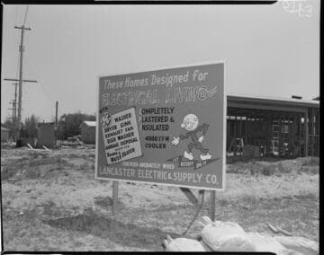 Sign with Reddy Killowatt at home construction site "These Homes Designed for Electrical Living"