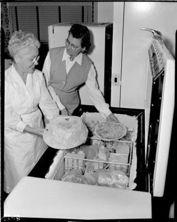 Two ladies taking food out of a deep freezer