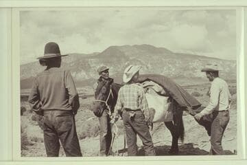 White-hat, Bahe, Nancy and Tom Daly pack for the trip to Arch in the Sky. Navajo Mountain in the background
