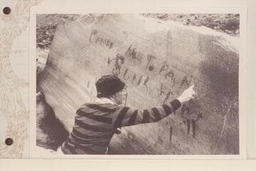 Dock Marston points up the Best Expedition inscription at Rapid 16 in Cataract CAnyon. "Camp NO 7 Hell To Pay No 1 Is Sunk & Down." Inscription was cut by Chief Boatman Harry McDonald after party had foundered boat No. 1 on July 21, 1891