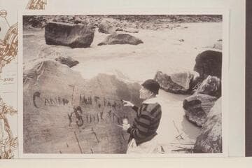 Dock Marston points up the Best Expedition inscription with water. The lower flat rock at upper center is the one which trapped the Boat No. 1 on July 21, 1891