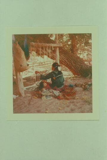 Squaw at the double job of weaving and baby sitting- Navajo Mt. Trading Post
