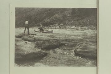 Identified by Emery Kolb as being in Red Canyon on the Green River. Note the figure on shore is wearing the dangerous choke-bored breeches and heavy boots. The boats were frequently stuck in the rocks through Red Canyon