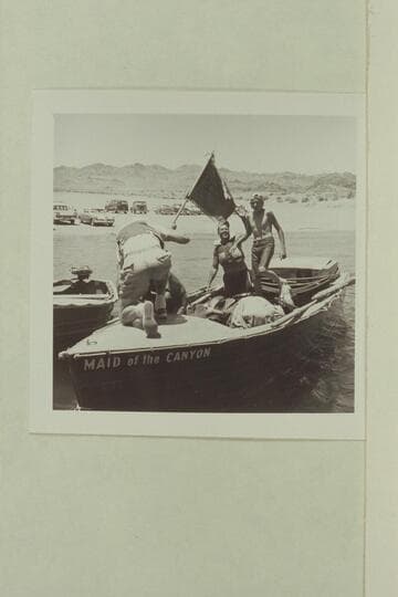 The "Maid of the Canyon" arrives at Boulder City. Roy Bolton waves as Jeff Marston steps forward. The Marine flag is being removed