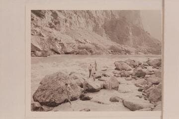 Lining of the Nevills skiffs at Lava Falls. Garth Marston is taking the stern line down at the left. John Riffey and Randall Henderson stand on the rocks taking instructions from Nevills. Kent Frost stands among the rocks at the right