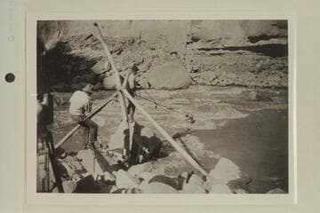 Emery Kolb "cooning" out to the trapped boat at Dark Canyon. USGS party under Chenoweth. Tasker is at left and Lint is center. Photo from Lint album