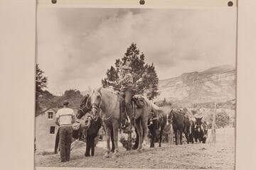 Nancy Daly leads the string out from Navajo Mountain Trading Post. Ralph Cameron watches from left