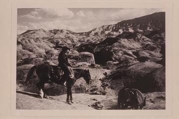 Dan Lehi rides down the slick rock from the rim of the mesa west of Nasja Creek. Cha Butte is upper left. Navajo Mountain is upper right. The sloping mesa at upper right is 4903. Nasja Creek is center