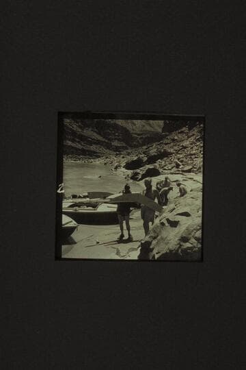 The spray shields ripped from the hulls in North Canyon Rapid. Holding the shields are Taylor and Desloge. In the background are Desloge, Sanderson, and Belknap