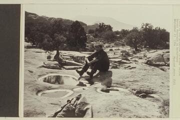 Pools in the slickrock in Bisha Canyon. Navajo Mt. in background