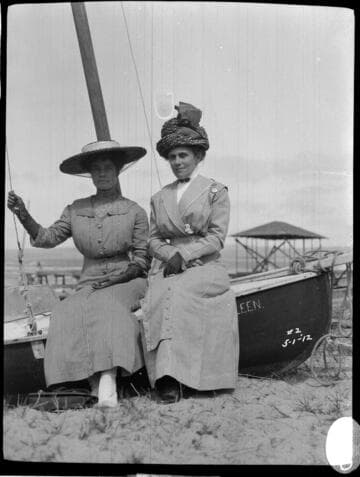 Two women sitting on the side of a boat on May 1. 1912. The boat's name is "Kathleen."