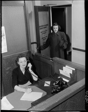 Receptionist on phone while young lady enters employment office at SCE