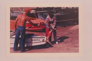 Sandra Nevills christening the "Sandra"; Lees Ferry. Before the start of the Grand Canyon run. Nevills at left and Doris Nevills at right
