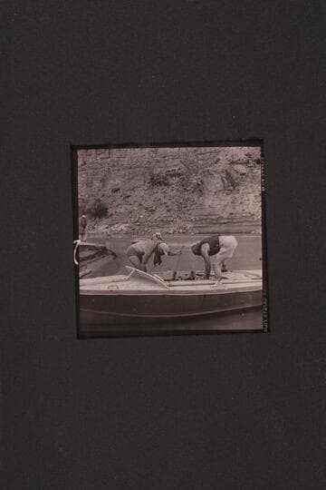 The boats used in the 1954, June traverse of Grand Canyon. Sanderson has fired up the motors of the "Rattlesnake" while Cutler holds the bow line. Marston is stowing the lines of the "BOOTOO" while Masland looks on