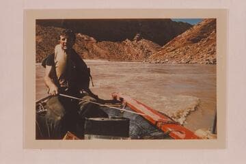 Don Hatch nursing the outboard motor on one of the boloney boats near Hance Rapid. He holds the line for support